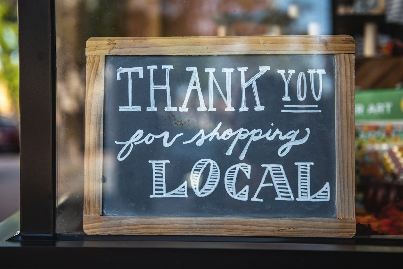 a sign that says "thank you for shopping local" displayed in a shop window