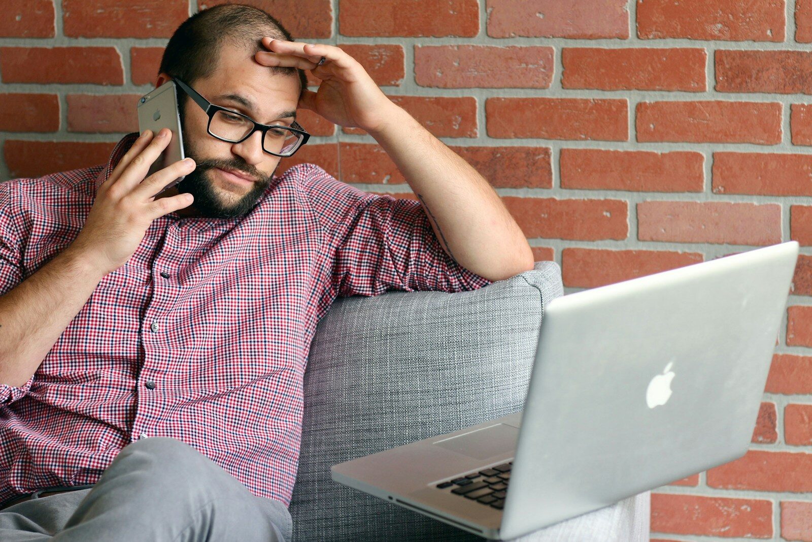 a frustrated man with a laptop talking on a cell phone